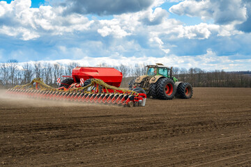 sowing work in the field in spring. Tractor with seeder