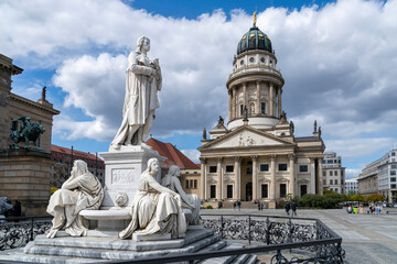 Berliner Gendarmenmarkt mit dem Schillerdenkmal und dem Französischen Dom an einem sonnigen Apriltag mit einigen Wolken © dL