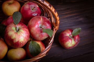 Red sweet apples in a basket on a textured wooden background