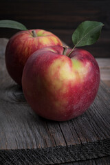 Two red sweet apples on a textured wooden background