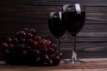 Glass with wine and grapes oon old wooden background