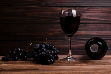 Glass with wine and grapes oon old wooden background