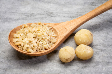 macadamia nut flour on a wooden spoon against rustic stone background, gluten-free starch substitute