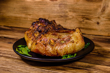 Baked piece of pork belly and parsley on a black plate