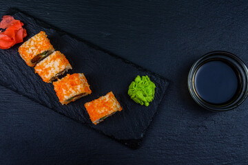 Sushi roll philadelphia with salmon, rice, cheese, cucumber, avocado and caviar on a slate board. Japanese food. Top view