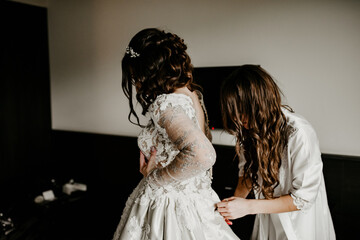 bride zipping buttoning her white wedding dress	