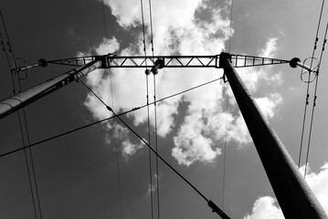 Power line pole and wires in black and white against cloudy sky