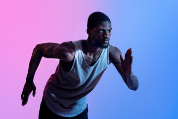 Portrait of young black sprinter running in neon light. Professional sports concept