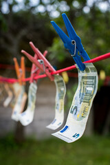 Money laundering. Money (EURO) banknotes hanging on a laundry line attached with colorful clips
