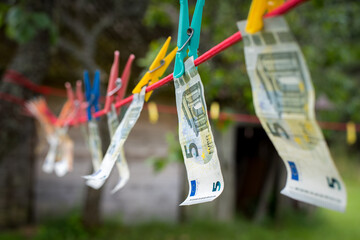 Money laundering. Money (EURO) banknotes hanging on a laundry line attached with colorful clips
