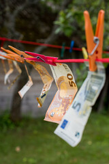 Money laundering. Money (EURO) banknotes hanging on a laundry line attached with colorful clips

