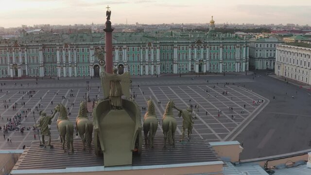 Aerial footage of Palace Square through a triumphal chariot, rear view, winged Nick, a symbol of military glory, over arch of the General Staff Building, the Aleksandr column, the Winter Palace