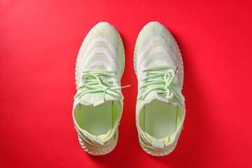 Women's green sneakers on a red background, top view, sport symbol