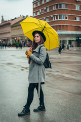 Woman holding a yellow umbrella during rain
