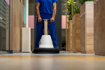 
Janitorial worker polishing hard floor with high speed machine in an office space.Focus is on the...