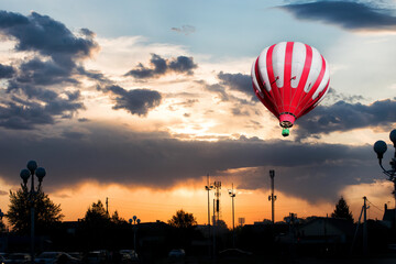 A red and white hot air balloon on background of bright sunset.