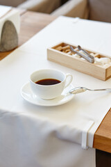 Hot coffee in a cup on wooden table. Modern design interior, restaurant blur background with bokeh image
