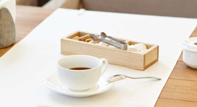 Hot coffee in a cup on wooden table. Modern design interior, restaurant blur background with bokeh image