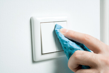 Cleaning A White Light Switch On A Wall With Wipe