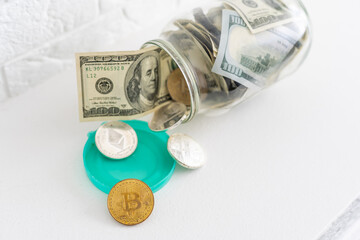 Bitcoins bronze golden coin in the glass jar on white wooden table. Set of cryptocurrencies with a real euro, dollars in the jar. Savings, investment, financial risk concept