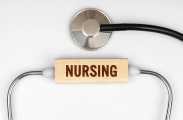 On the table is a stethoscope and a wooden plate with the inscription - NURSING