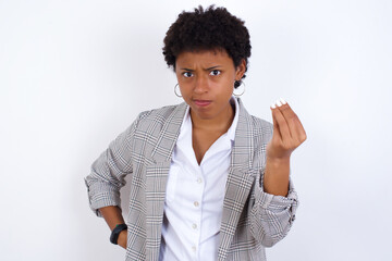 African American businesswoman with curly bushy hair wears  formal clothes over white background angry gesturing typical italian gesture with hand, looking to camera