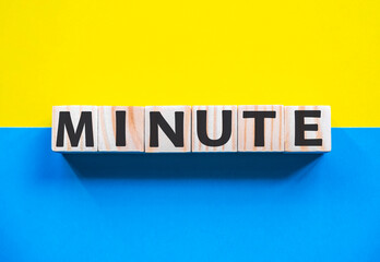 Word MINUTE on wooden cubes with word on beautiful yellow and blue background. Business, media marketing concept.