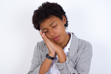 Fototapeta na wymiar African American businesswoman with curly bushy hair wears formal clothes over white background sleeping tired dreaming and posing with hands together while smiling with closed eyes.