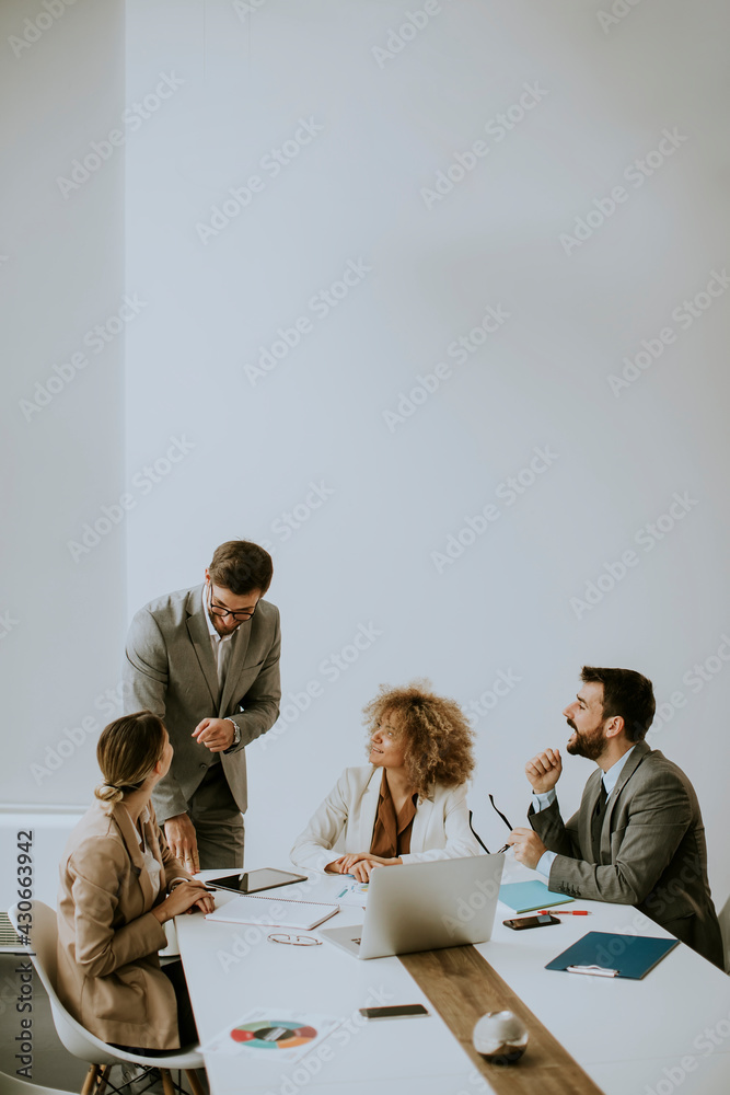 Wall mural group of young business people working and communicating while sitting at the office desk together