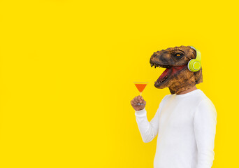 Happy man wearing dinosaur head mask with martini glass in hand and red beverage.