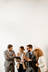 Multiethnic business people using digital tablet while standing by the wall in the office