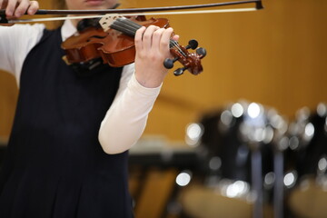 A girl student plays a musical instrument on the violin with a bow at a school concert.Close-up...