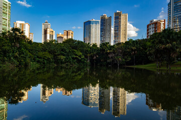 Obraz premium Paisagem com prédios e árvores, com reflexo na água do lago. Foto feita no Parque Flamboyant.