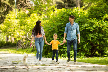 Happy family with cute bichon dog in the park