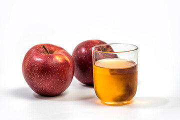 Close up of a glass of apple juice, with a whole and half apple. Natural apple juice on white background