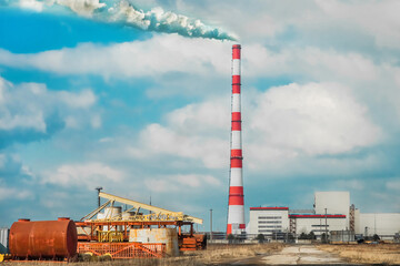 Industrial zone, construction outdoor site of a thermal power plant with chimney on a background of cloudy sky