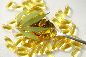 Cannabis oil capsule concept, CBD oil capsules and hemp leaves. Macro close up of capsules of biological and ecological hemp plant herbal pharmaceutical.