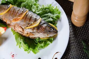 fried fish stuffed with lemon slices on a white plate with a lettuce leaf