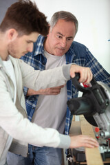 Obraz premium student and teacher in carpentry class using circular saw