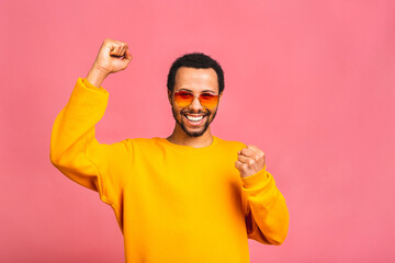 Cheerful handsome African american guy making yes gesture while excited about winning. Ecstatic young fan rooting and expressing support. Success concept.