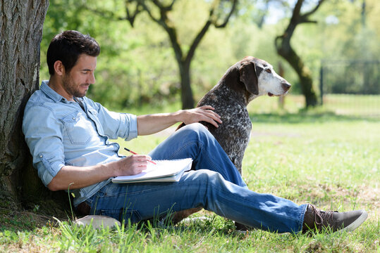 man relaxing in park with dog