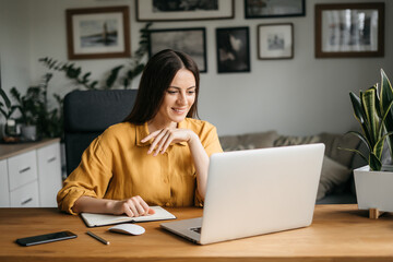 Head shot pleasant happy young woman freelancer working on computer at home. Attractive businesswoman studying online, using laptop software, web surfing information or shopping in internet store.
