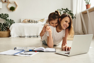 mom works at the computer while playing with her daughter