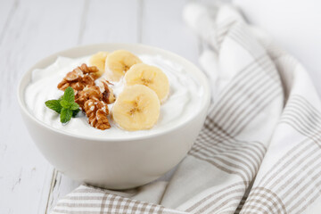 Healthy breakfast of yogurt with banana, walnuts and cinnamon
