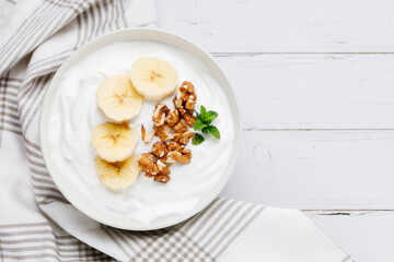 Healthy breakfast of yogurt with banana, walnuts and cinnamon