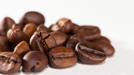 black coffee beans on a white background. Close-up of roasted coffee beans heap isolated on white. aromatic morning drink, invigorating black coffee. macro photo, close-up, on a white background