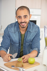 Fototapeta premium man cut kiwi fruits in slices on the table