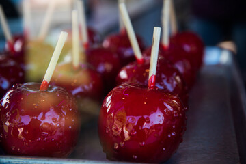 Candied apples sit in a display case for sale.