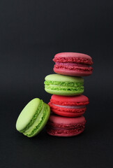 Multicolored almond cakes with pistachio, raspberry and currant cream (macarons) on a dark background