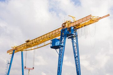 Overhead industrial crane at a construction site against the background of the sky